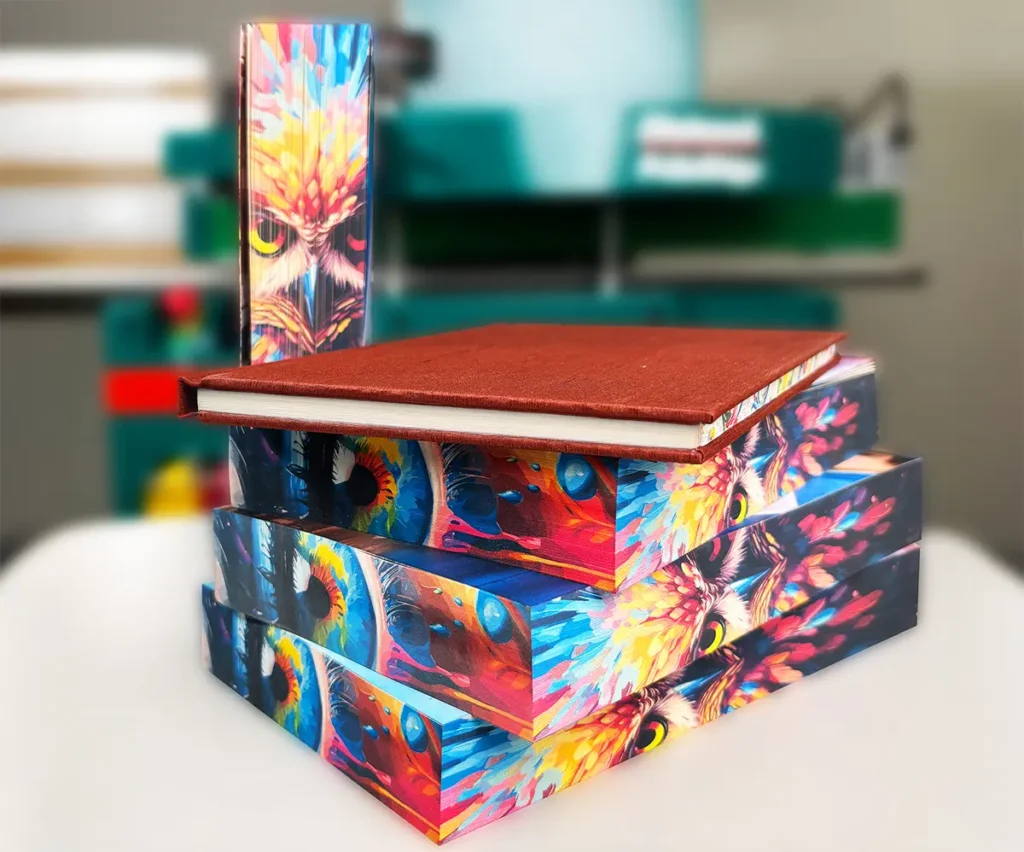 Impresión de Cantos de Libros con Diseño Abstracto Pila de libros de tapa dura con cantos impresos en colores vibrantes y diseño abstracto, reflejando la fusión entre arte y tecnología.